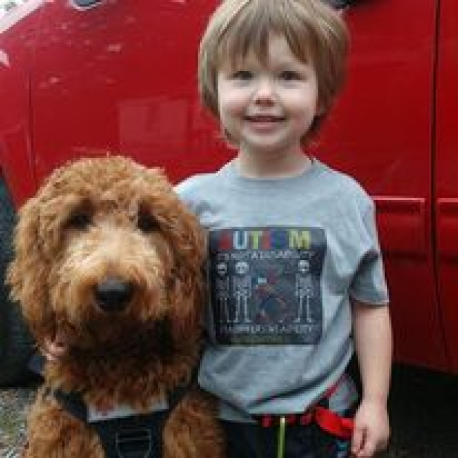 Photo of a smiling boy with his service dog.