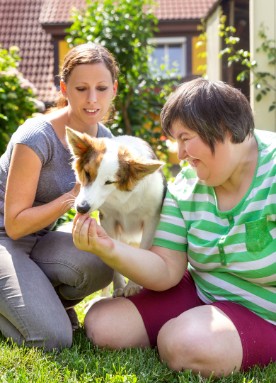 Mentally challenged woman and another woman attend to a companion dog